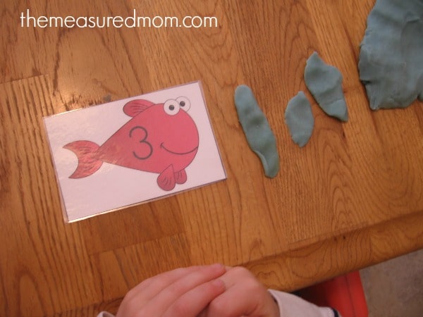child making playdough worms for fish card
