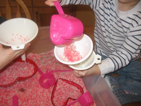 children dumping rice into funnels
