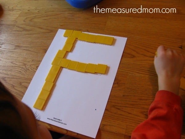 child placing tiles on block letter F