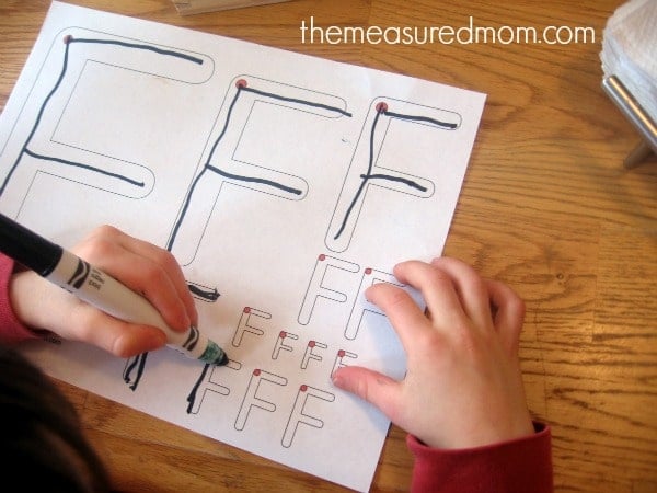 child writing on letter F worksheet