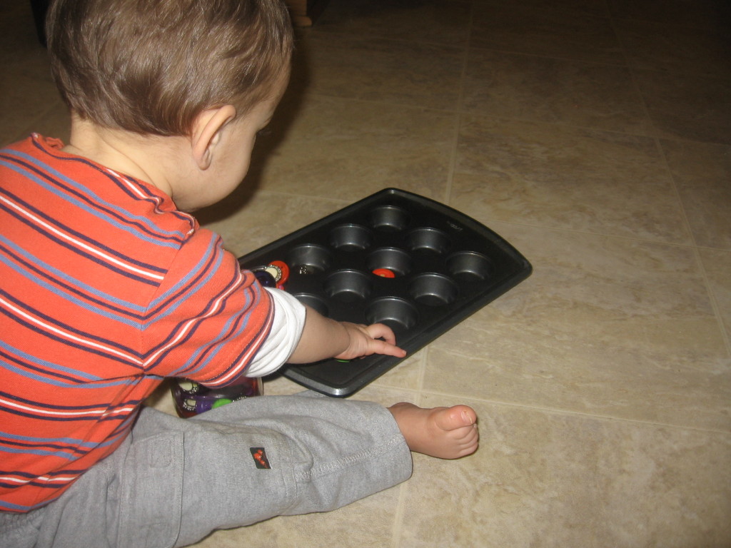 child placing button into muffin tray