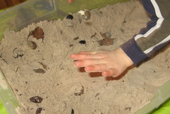 child patting down sand