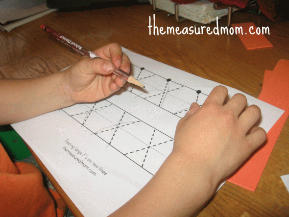 child writing on letter X worksheet