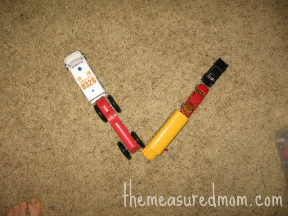 child with V made out of toy vehicles