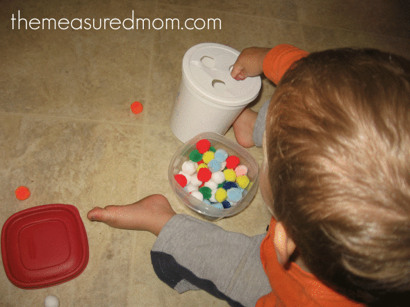 child poking pom-poms through holes