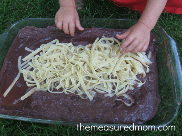child playing with linguine and chocolate pudding