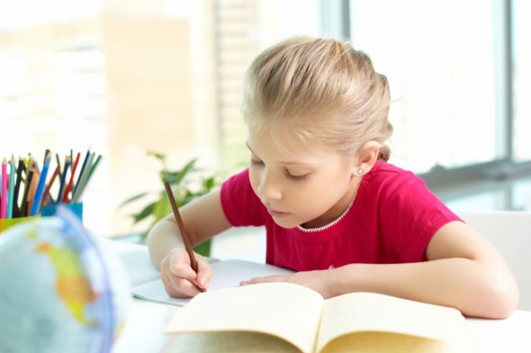 Portrait of lovely girl drawing with pencil in copybook